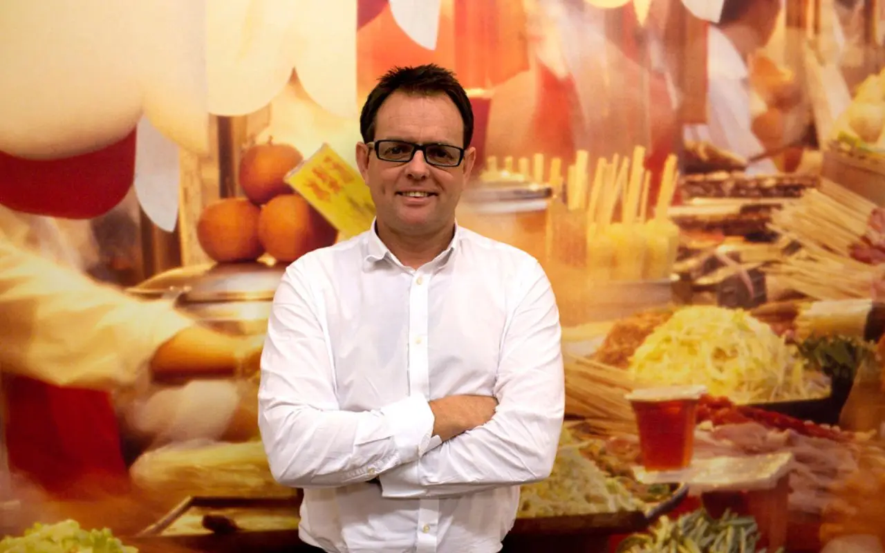 David Fox, founder of Tampopo, in front of a street food mural